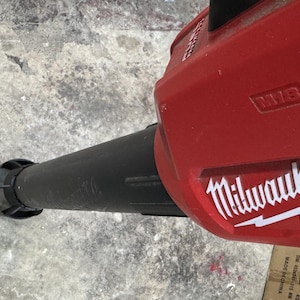 May include: A red and black Milwaukee FUEL cordless leaf blower. The blower has a black nozzle and a red body with the Milwaukee logo in white. The image is taken from an overhead angle.