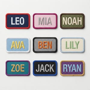 May include: Nine rectangular embroidered name patches arranged in a grid. The patches feature various color combinations including navy with red, pink with magenta, olive with brown, light blue with white, gray with black, cream with blue, teal with purple, black with blue, and purple with gold borders.