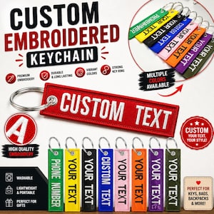 May include: A rectangular red fabric keychain with white embroidered text reading CUSTOM TEXT, attached to a silver metal ring. Below, a row of eight additional keychains in green, yellow, black, blue, pink, orange, purple, and olive green.
