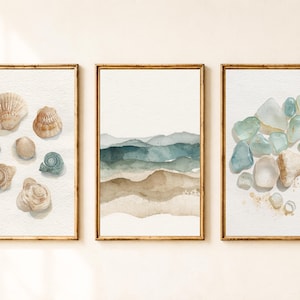 Puede incluir: Un conjunto de tres cuadros de pared. La lámina de la izquierda muestra varias conchas marinas en tonos beige y azul. La lámina central presenta capas abstractas de acuarela en tonos azul, verde y beige. La derecha muestra cristales de mar.