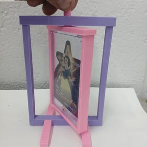 May include: A 3D-printed, pink and purple picture frame with a Snow White image. The frame is supported by two pink legs and a purple rectangular frame. The image is held in a pink frame and is titled "Once Upon a Star".