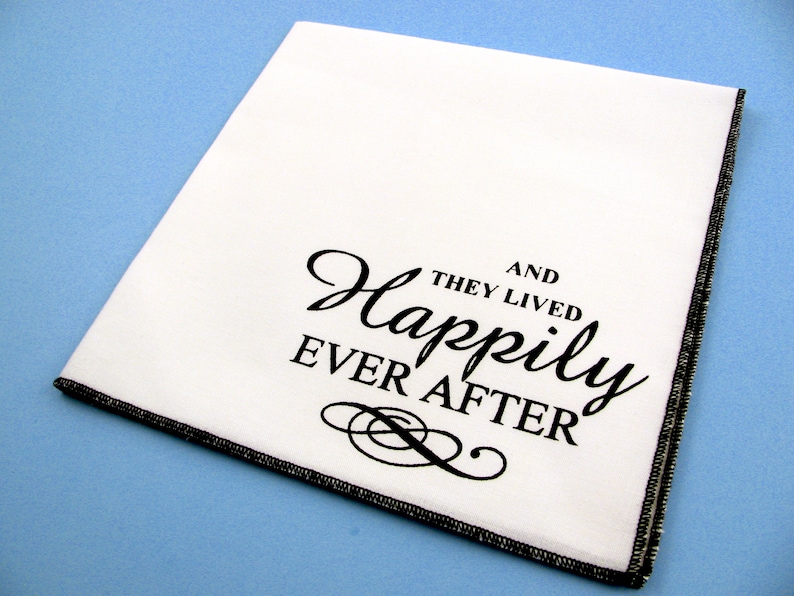 May include: White fabric napkin with black text that reads "And they lived happily ever after".