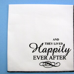May include: White fabric napkin with black embroidered text that reads "And they lived happily ever after" with a decorative flourish.