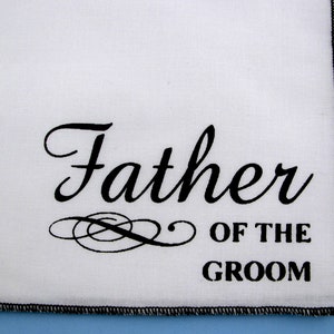 May include: White handkerchief with black embroidered text that reads "Father of the Groom".