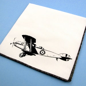 May include: A black and white illustration of a vintage biplane on a white fabric background.
