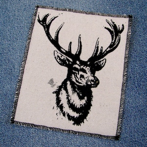 May include: Black and white illustration of a deer head with large antlers on a white background. The deer head is centered on the patch, which has a black stitched border.