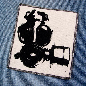 May include: Black and white patch of a gas mask with a white background.
