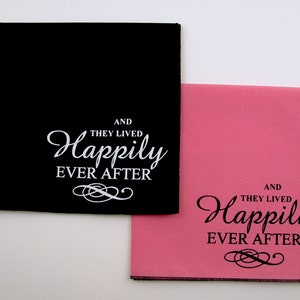 May include: Two fabric napkins with the text "And they lived happily ever after" printed on them. One napkin is black with white text and the other is pink with black text.