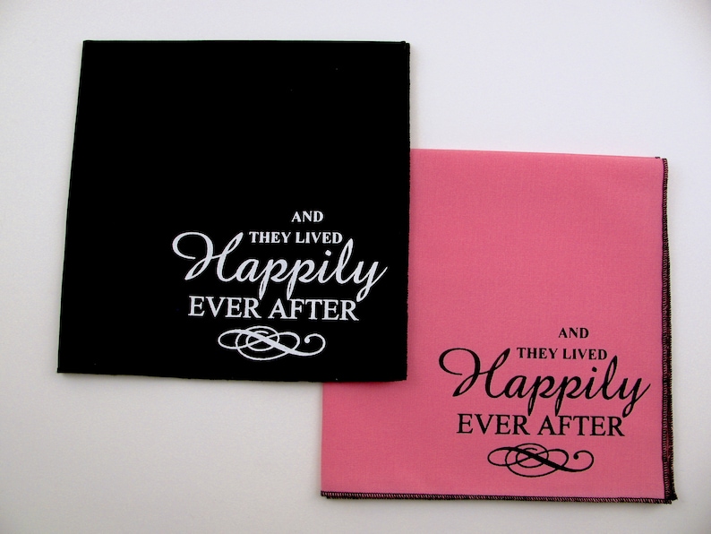 May include: Two fabric napkins with the text "And they lived happily ever after" printed on them. One napkin is black with white text and the other is pink with black text.