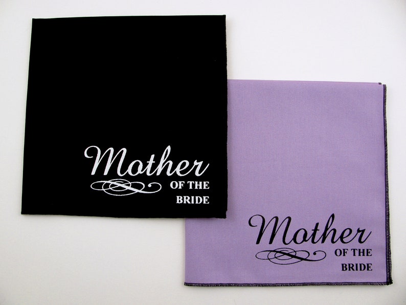 May include: Two black and lavender fabric squares with white text that reads "Mother of the Bride".