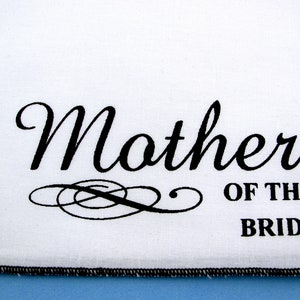 May include: White fabric with black text that reads "Mother of the Bride".