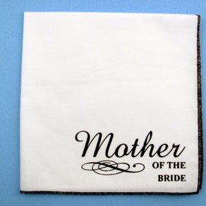 May include: White handkerchief with black embroidered text "Mother of the Bride" and a decorative flourish.