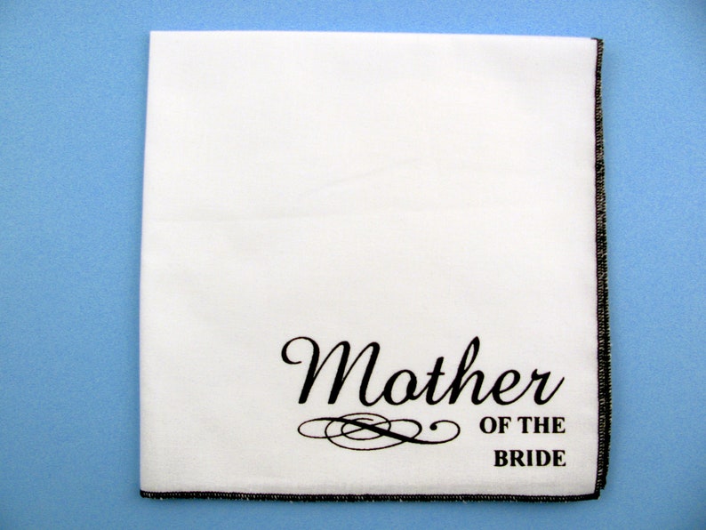 May include: White handkerchief with black embroidered text "Mother of the Bride" and a decorative flourish.