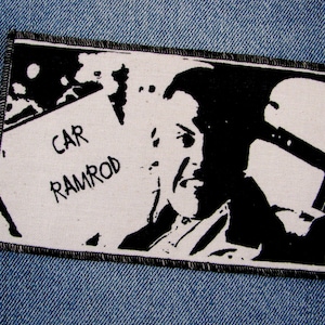 May include: Black and white iron-on patch featuring a silhouette of a person's head and the text "CAR RAMROD".