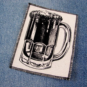 May include: A black and white illustration of a glass mug filled with a dark liquid and foam on top. The mug has a handle and is on a white background.