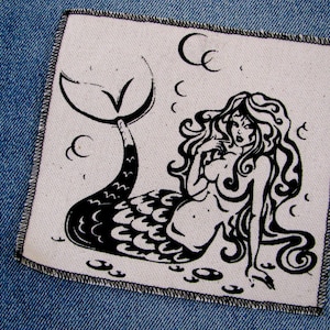 May include: Black and white illustration of a mermaid with long flowing hair and a scaly tail. The mermaid is sitting on a white background with a few bubbles around her.