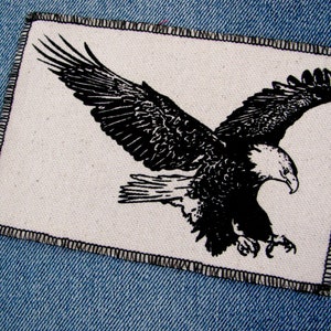 May include: Black and white embroidered patch of an eagle with wings spread, on a white background.