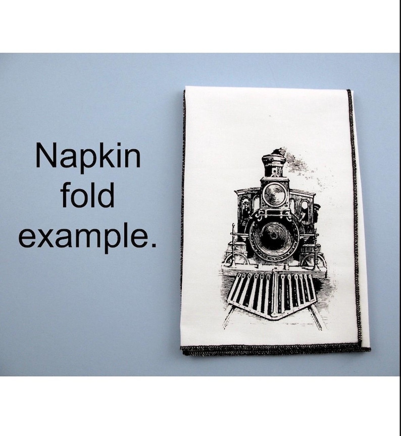 May include: A white napkin with a black and white illustration of a vintage steam locomotive. The napkin is folded in half and has a black border.