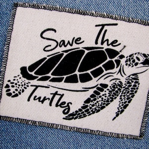 May include: White fabric patch with black text and a black silhouette of a sea turtle. The text reads "Save The Turtles".