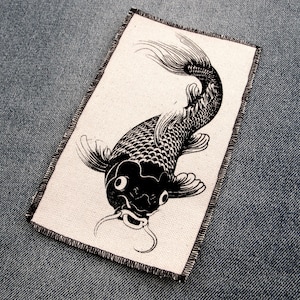 May include: Black and white illustration of a koi fish on a white canvas patch. The fish is swimming to the right and has a large, open mouth.