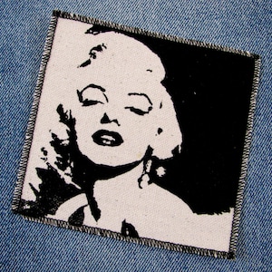 May include: Black and white image of Marilyn Monroe on a white fabric patch with black stitching around the edges.