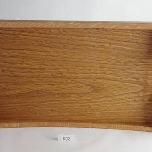 May include: A rectangular wooden serving tray with a natural wood grain finish. The tray has curved sides and handles wrapped in orange twine. The tray is designed for serving food or drinks.