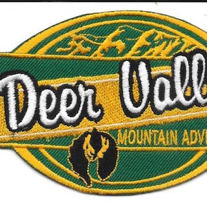 Puede incluir: Parche bordado con el texto "Deer Valley Mountain Adventure" en blanco y amarillo. El parche presenta un fondo verde con un borde amarillo y un emblema negro y amarillo.