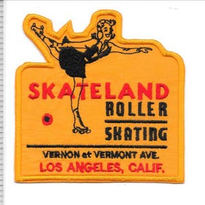 Op de afbeelding: Een oranje patch met een zwart-wit rolschaatserontwerp. De patch leest "SKATELAND ROLLER SKATING" en bevat het adres "VERNON et VERMONT AVE. LOS ANGELES, CALIF." De patch is ongeveer 7.6 cm breed.