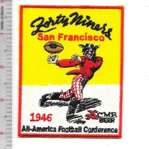 May include: A rectangular embroidered patch with a yellow and white background featuring a football player in a red jacket and checkered pants catching a football. Text includes Forty Niners, San Francisco, 1946, Acme Beer, and All-America Football Conference. A ruler shows a height of 4 inches.