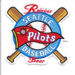 Puede incluir: Parche bordado con el logotipo del equipo de béisbol Seattle Pilots. El diseño incluye una pelota de béisbol, bates cruzados y una pancarta con la inscripción "Pilots". El parche es azul, rojo, blanco y marrón, con "Rainier" arriba y "Beer" abajo.