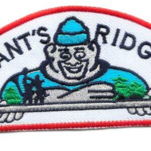 Pode incluir: Patch bordado com o texto "GIANT'S RIDGE" e um personagem de desenho animado segurando uma bandeja com árvores. O patch tem um fundo branco com uma borda vermelha. O personagem usa um chapéu e uma camisa azuis.