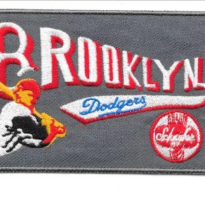 May include: Embroidered patch featuring the word "BROOKLYN" in red and white, with "Dodgers" in blue script. Includes a baseball player graphic and a red and white "Schaeffer" logo. The patch is rectangular and gray.