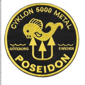 Puede incluir: Un parche bordado circular con fondo negro y borde amarillo. Presenta un gráfico de un pez amarillo, un tridente y el texto CYKLON 5000 METAL, GÖTEBORG, SWEDEN y POSEIDON. Una regla muestra que el parche mide aproximadamente 11,5 cm de ancho.