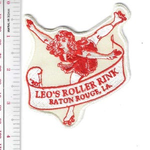 May include: Embroidered patch featuring a red figure skating design with the text "LEO'S ROLLER RINK BATON ROUGE, LA." The patch is approximately 3 inches tall and 3 inches wide.