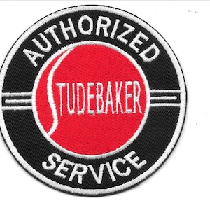 Puede incluir: Parche bordado con borde negro y texto blanco que dice "AUTHORIZED SERVICE" alrededor de un círculo rojo. El texto "TUDEBAKER" está en blanco dentro del círculo rojo. Una regla está en el lado izquierdo.
