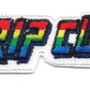May include: A colorful embroidered patch with the text "RIP CURL" in a rainbow gradient. The patch has a white border and is approximately 3 inches long.