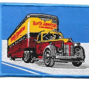 May include: Embroidered patch featuring a vintage red and yellow North American truck with the text "North American" on the trailer. The patch is bordered in blue and set against a blue background.