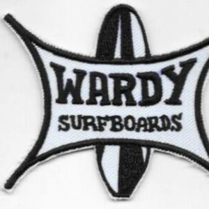 May include: A black and white embroidered patch with the text "WARDY SURFBOARDS" in bold letters. The patch has a unique shape with a surfboard design in the center and a starburst-like outline.