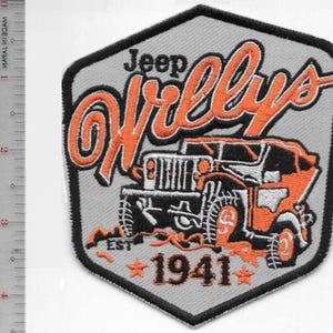 Może przedstawiać: Haftowana naszywka z szarym tłem i czarną obwódką. Naszywka zawiera napis "Jeep Willys" pomarańczową czcionką nad pomarańczową i czarną ilustracją pojazdu Jeep. Rok "1941" znajduje się pod pojazdem.