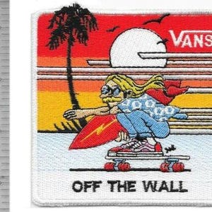 Puede incluir: Parche bordado con un skater de dibujos animados con pelo rubio, gafas de sol y una capa roja, montando en monopatín. El fondo muestra una puesta de sol con una palmera y el logo de Vans. Texto: "OFF THE WALL".