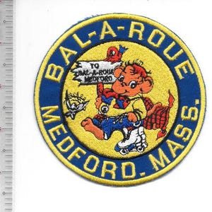 Puede incluir: Parche circular con borde azul y centro amarillo. El texto "BAL-A-ROUE MEDFORD. MASS." rodea a un personaje de dibujos animados sobre patines. El personaje sostiene un letrero que dice "TO BAL-A-ROUE MEDFORD."