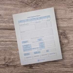 Può includere: Un foglio di carta bianco con il testo blu "HVAC Engineer Report". Il documento presenta righe e colonne con intestazioni blu e campi di testo. La carta è su una superficie di legno.