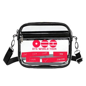 May include: Clear crossbody bag with a black trim and strap. The bag features a red and white graphic with the text "BTS WORLD TOUR" and the names of the band members. The bag has a zippered main compartment and a front pocket.