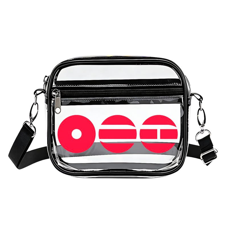 May include: Clear crossbody bag with a black strap and trim. The bag features a white panel with three red circular designs. A zippered pocket is visible on the front.