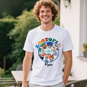 May include: White t-shirt featuring the word "ZOOTOPIA" in colorful letters above a circular graphic of characters from the animated movie. The name "Ryan" is printed below the graphic.