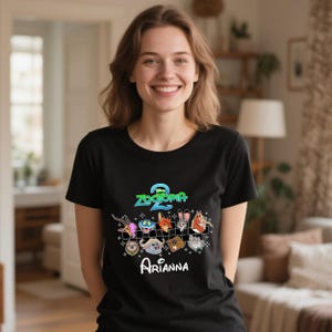 May include: Black t-shirt featuring the "Zootopia 2" logo and various cartoon animal characters. Below the design is the name "Arianna" in a cursive font. The shirt is a crew neck style.
