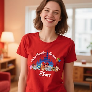 Puede incluir: Una camiseta roja con la frase "Making Memories Together" y el nombre "Eimee". El dise&ntilde;o incluye un castillo azul y personajes de dibujos animados. La camiseta es de manga corta.