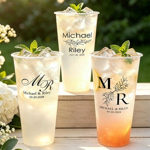Könnte beinhalten: Drei durchsichtige Kunststoffbecher gefüllt mit Eis und einem hellen Getränk, jeweils garniert mit einem Minzzweig. Die Becher tragen schwarzen Text: Michael Riley May 20, 2028, MR Michael & Riley 05.20.2028 und M R MICHAEL & RILEY 05.20.2028.
