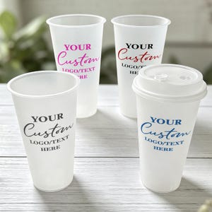 May include: Four translucent plastic cups with lids, each featuring the printed text YOUR Custom LOGO/TEXT HERE in different colours including pink, black, red, and blue. The cups have a smooth, matte finish and a tapered cylindrical shape.