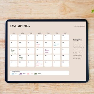 May include: A digital tablet displays a beige monthly family calendar for January 2026. The calendar includes dates, event categories, and a color-coded family member key. A white stylus and a plant are on the wooden surface.
